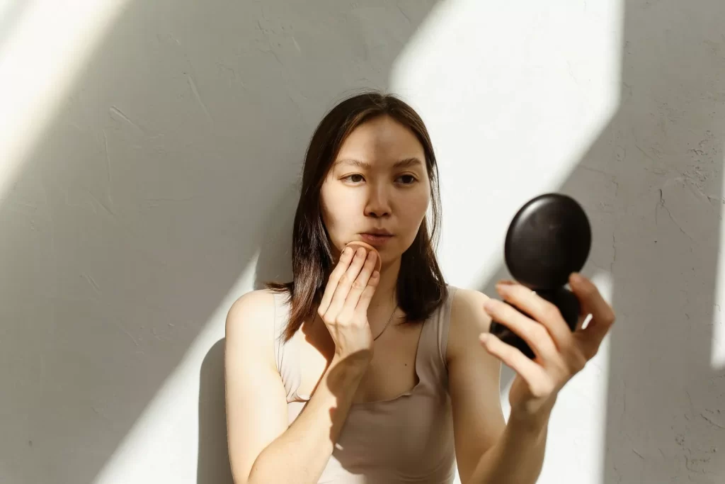 女性对镜涂抹护肤品,自然光线