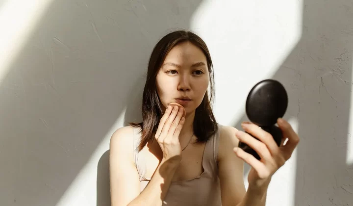 女性对镜涂抹护肤品,自然光线