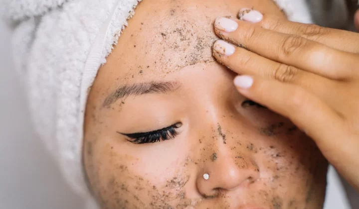 女性头裹毛巾涂抹面部磨砂膏