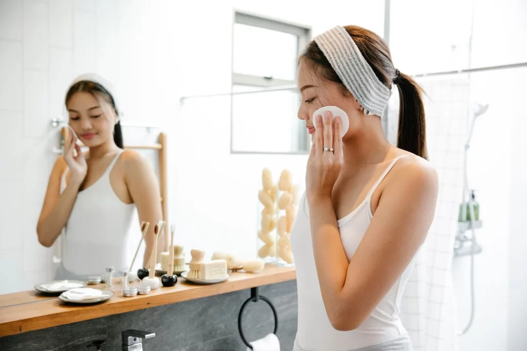 女性在浴室镜前用化妆棉擦拭面部