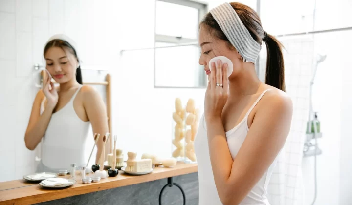 女性在浴室镜前用化妆棉擦拭面部