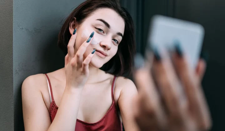 女性对镜微笑涂抹保湿霜