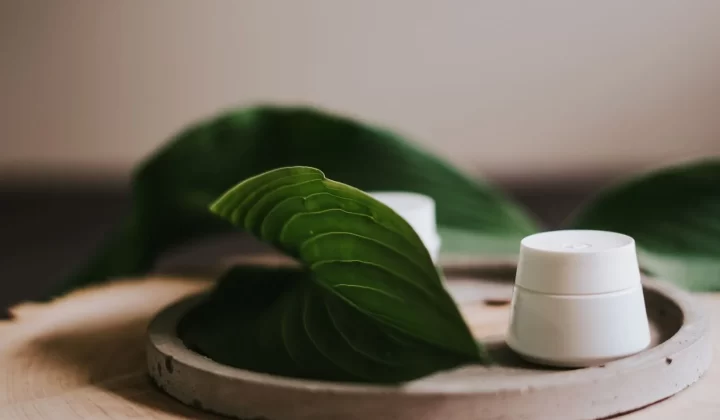 木托盘上的护肤霜容器搭配绿叶