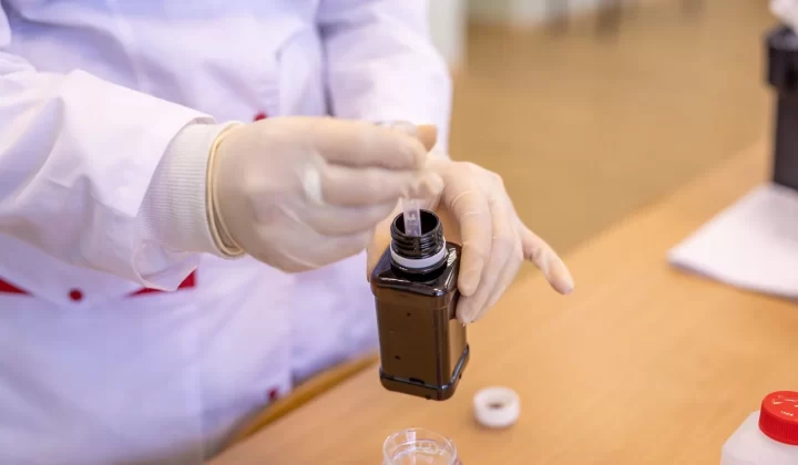 戴防护装备的科学家在实验室提取液体样本