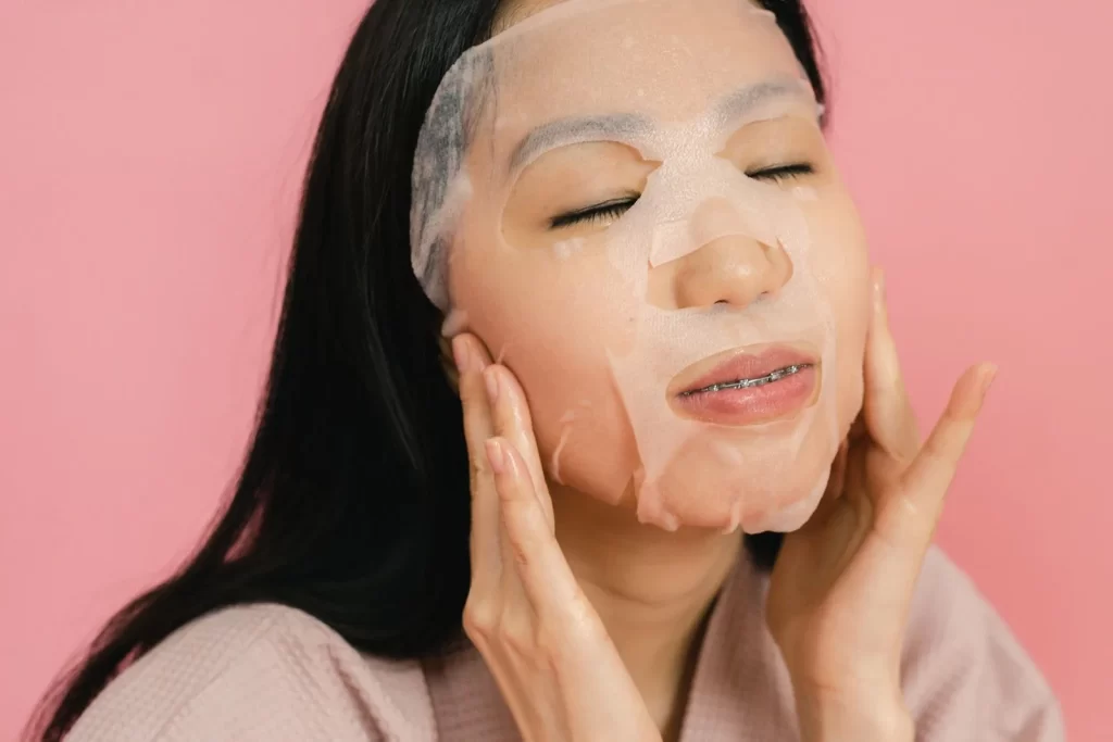亚洲女性敷补水面膜,粉色背景