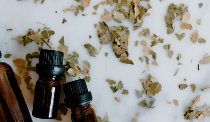精油瓶搭配散落干草药叶片平铺