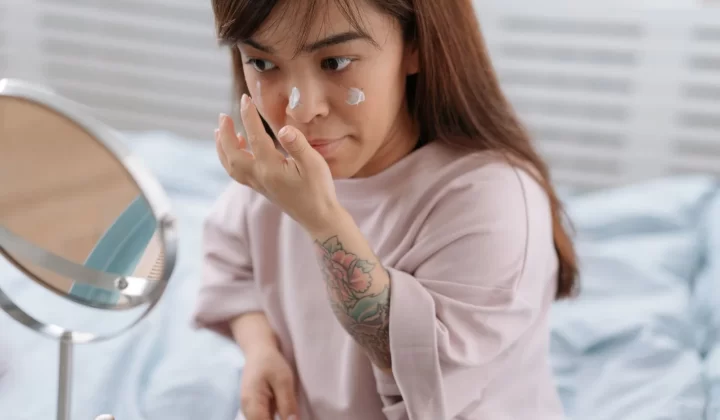 女性在卧室涂抹面霜,晨间护肤