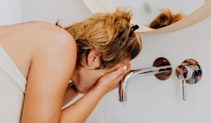 女性在现代浴室水槽前洗脸