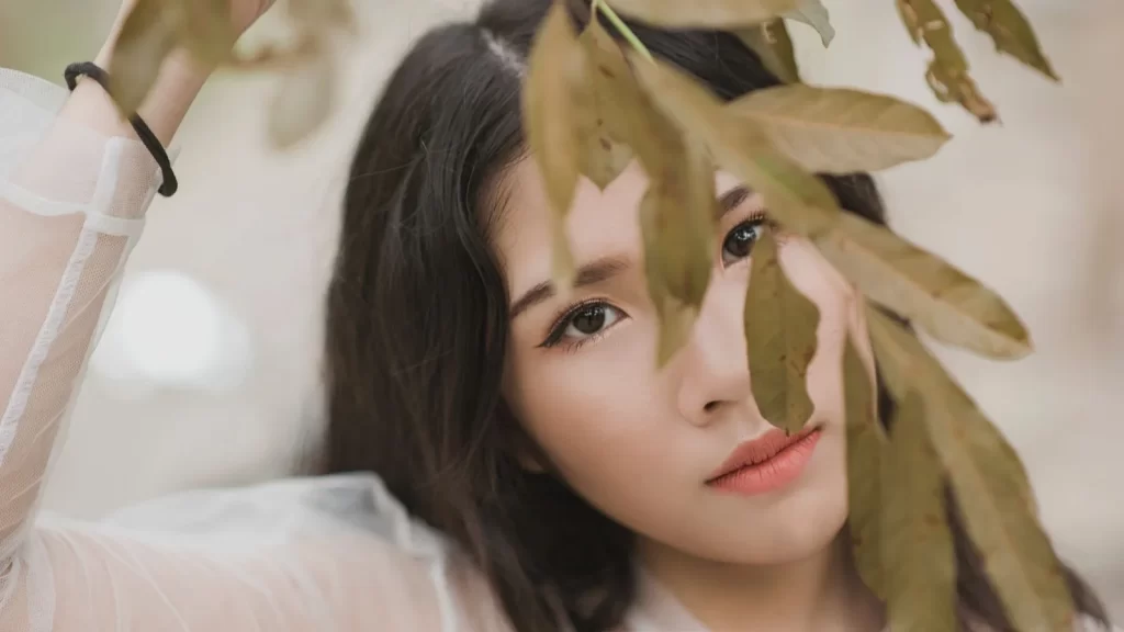 女性肖像被树叶部分遮挡,展现自然美