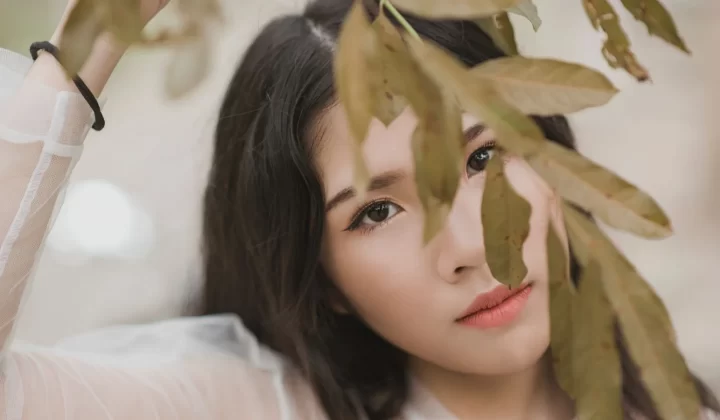 女性肖像被树叶部分遮挡,展现自然美