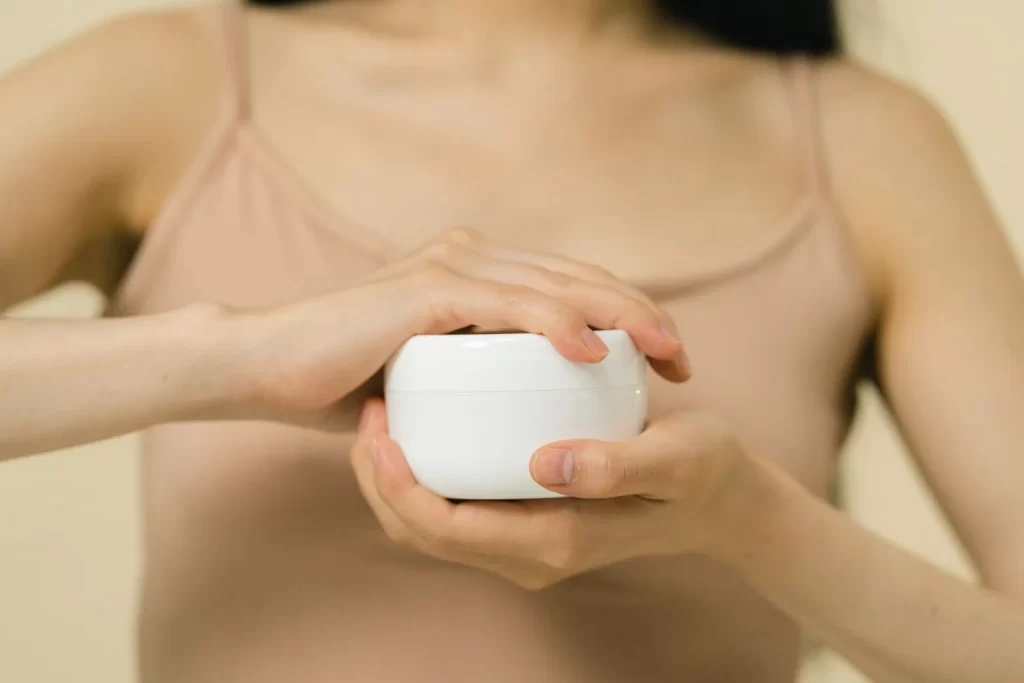 女性涂抹保湿霜特写,聚焦双手和容器