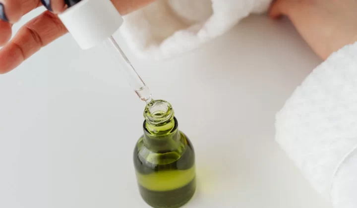 双手用滴管取用绿色精华瓶特写