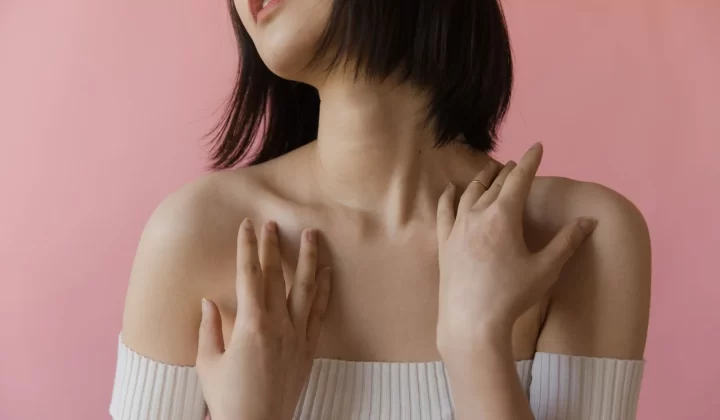 女性肖像特写,双手轻触肩部粉色背景