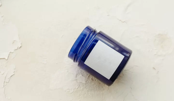 蓝色药膏容器放在米色纹理背景上