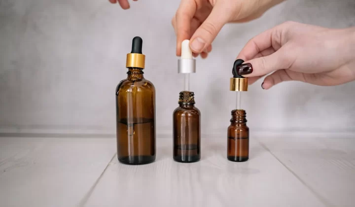 双手持有棕色滴管瓶特写