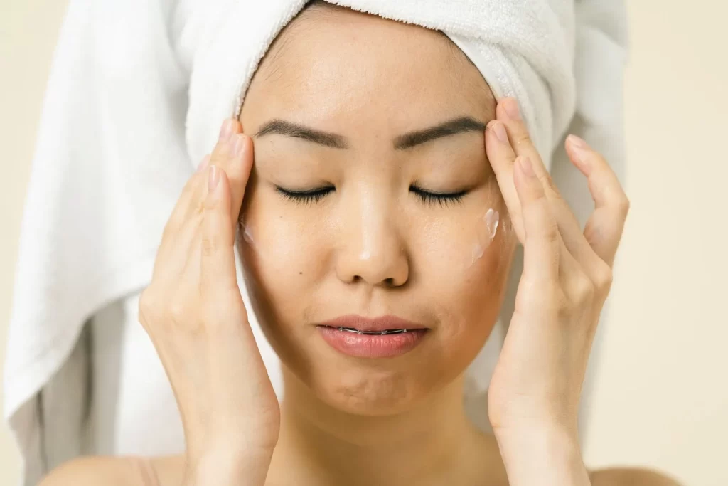 女性头裹毛巾涂抹保湿霜护肤
