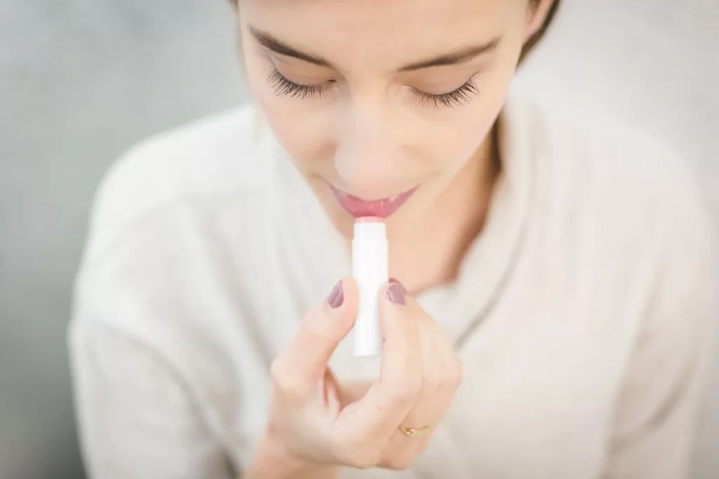 女性涂抹浅色润唇膏特写
