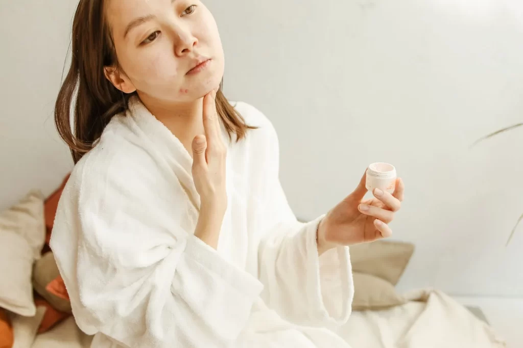 成年女性穿浴袍涂抹面霜进行护肤