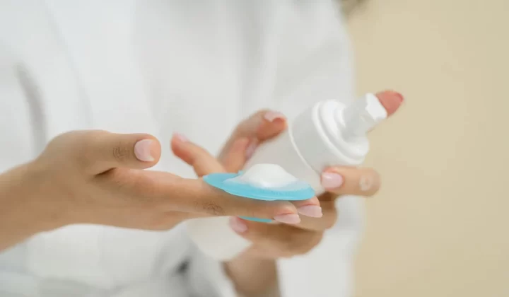 双手拿瓶子将泡沫倒在洁面垫上特写