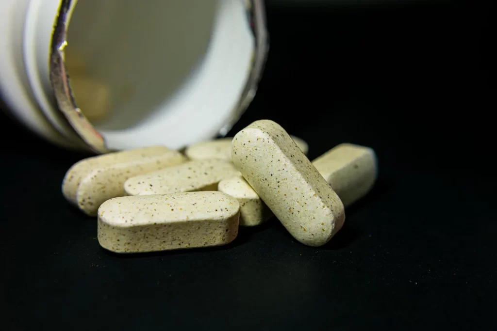 白色胶囊药丸从瓶中散落,黑色背景