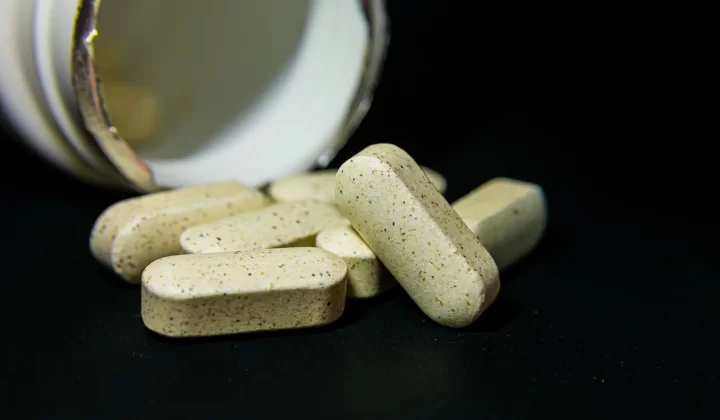 白色胶囊药丸从瓶中散落,黑色背景