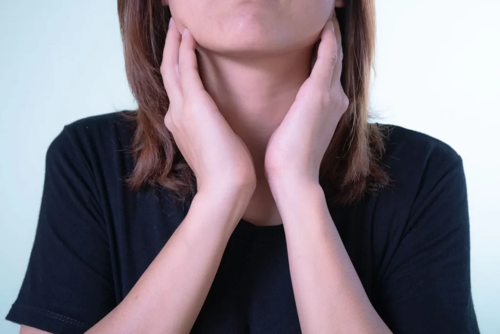女性双手触摸颈部特写,可能表示不适