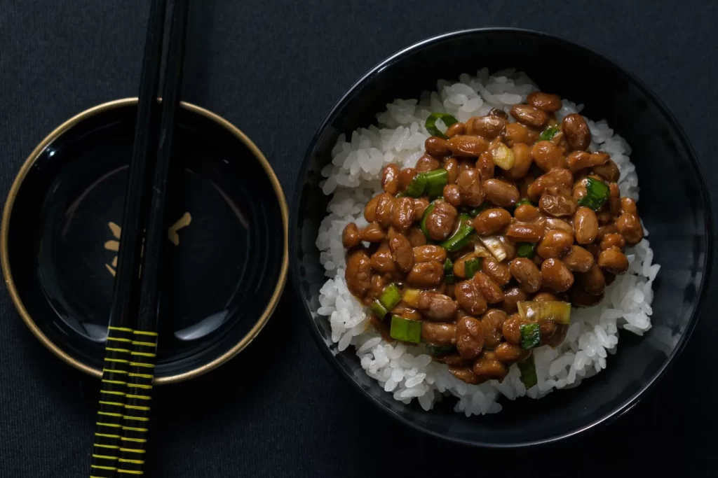 黑色碗中的纳豆黄豆搭配白米饭和筷子
