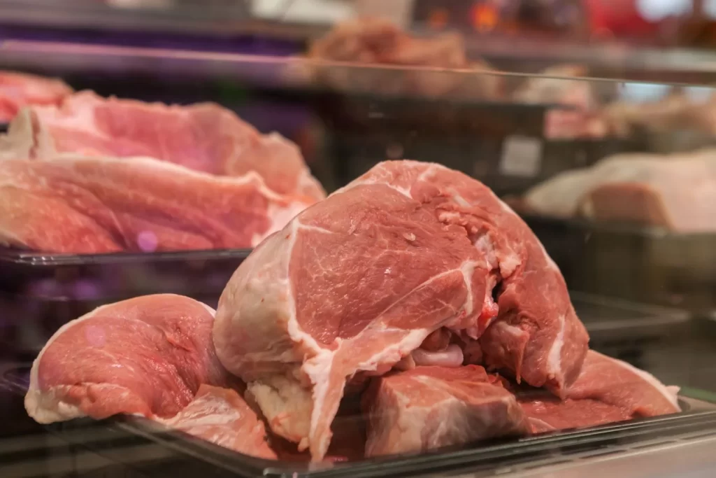 新鲜生猪肉块陈列在市场玻璃柜中特写