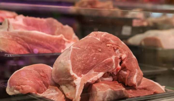 新鲜生猪肉块陈列在市场玻璃柜中特写