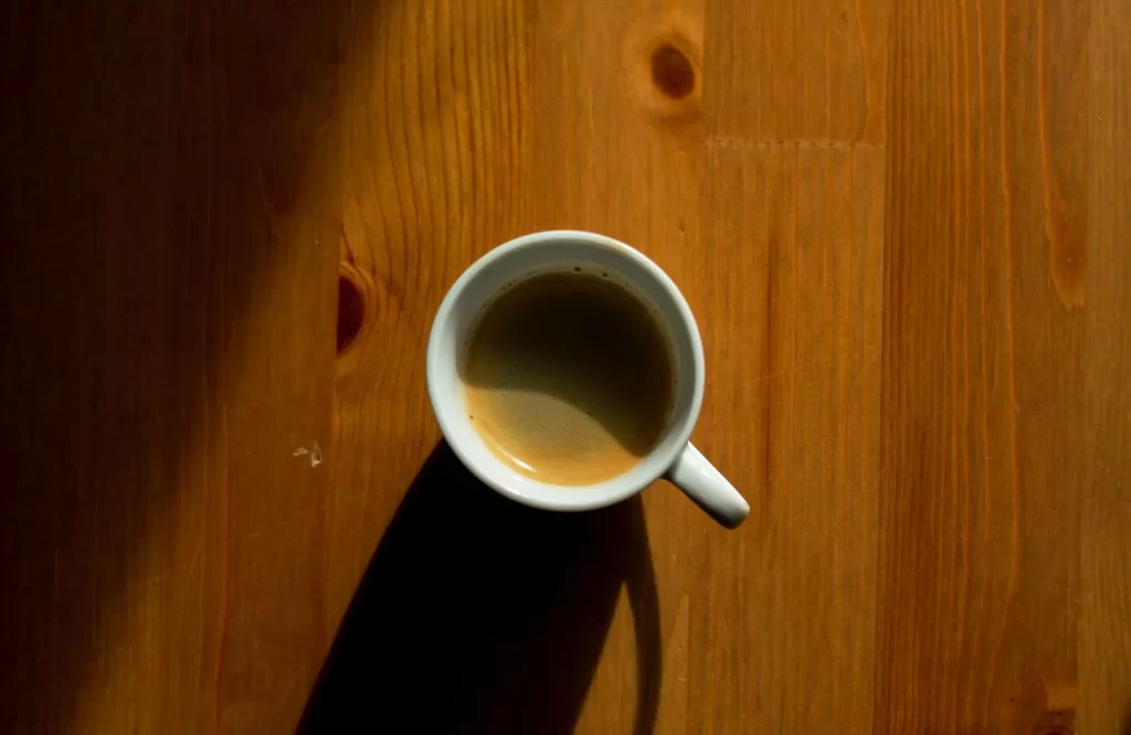 极简咖啡杯投下阴影,放在木质桌面上