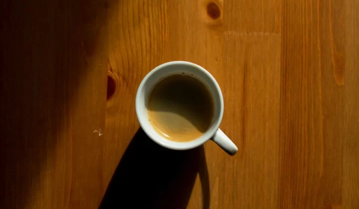 极简咖啡杯投下阴影,放在木质桌面上