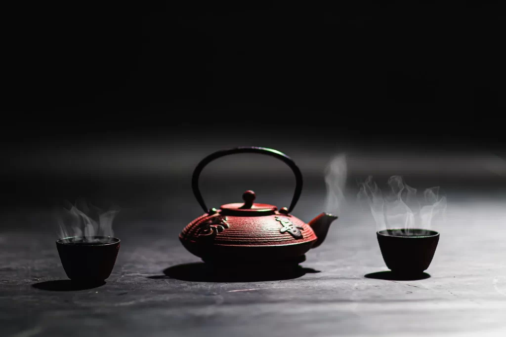 极简铸铁茶壶搭配冒着热气的茶杯,传统茶文化主题