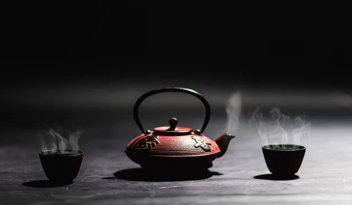 极简铸铁茶壶搭配冒着热气的茶杯,传统茶文化主题