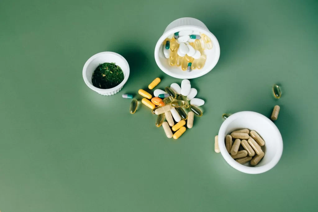 多种草本和维生素药丸胶囊放在绿色表面