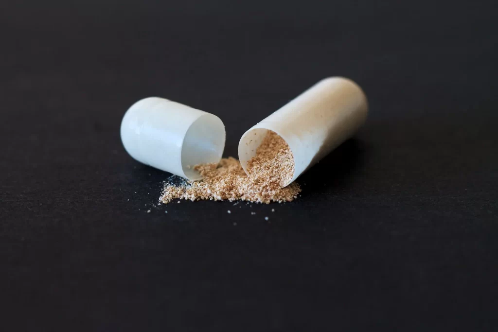 裂开的胶囊粉末洒落在深色表面,象征药物和健康