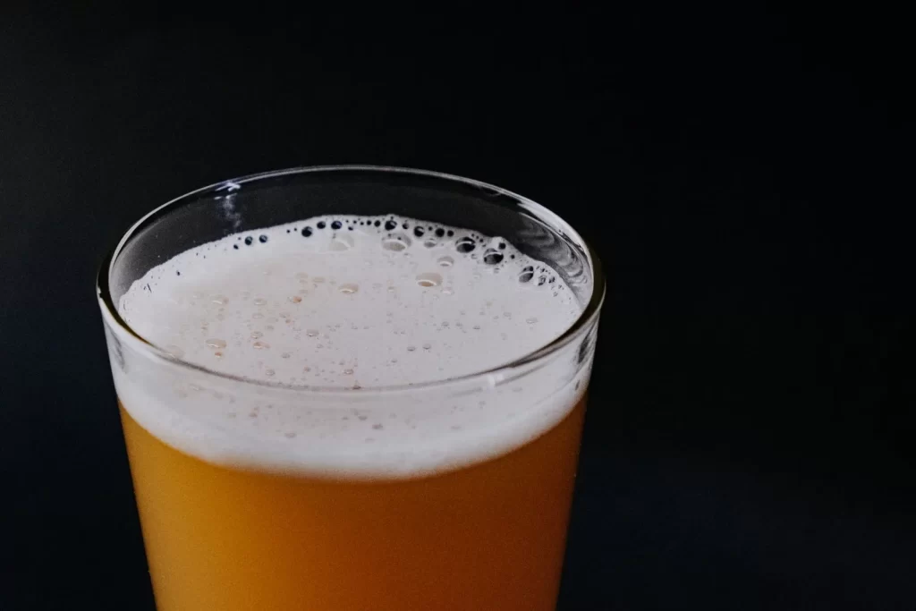 泡沫啤酒杯特写,黑色背景突出泡沫和气泡