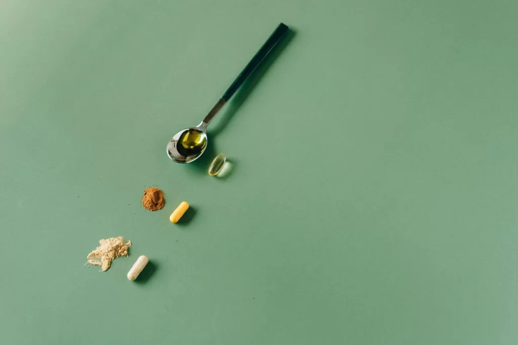 各种草本补充剂和粉末放在绿色背景上,搭配勺子