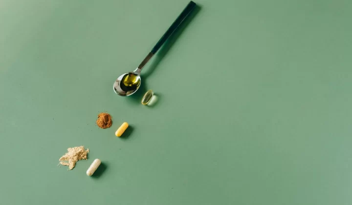 各种草本补充剂和粉末放在绿色背景上,搭配勺子