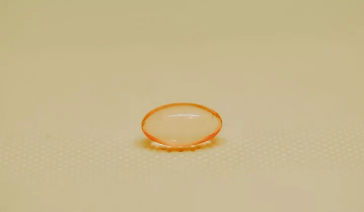 单颗橙色药用胶囊放在纹理表面特写