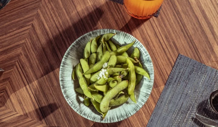 新鲜毛豆撒盐俯拍,放在时尚木质桌面上