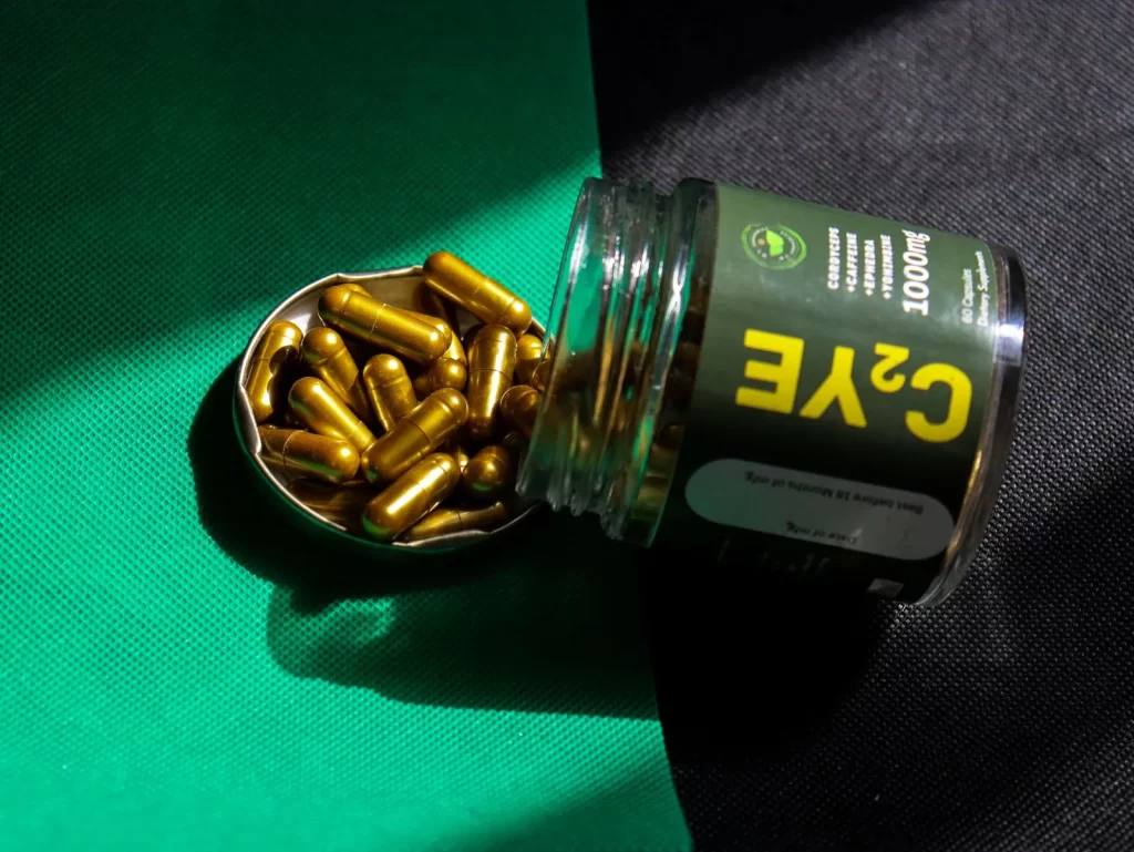 金色胶囊从罐中溢出,放在绿色和黑色布料上