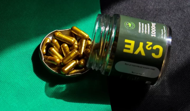 金色胶囊从罐中溢出,放在绿色和黑色布料上