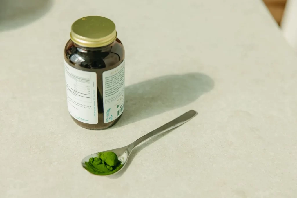 罐子和勺子装满绿色粉末特写,健康保健主题