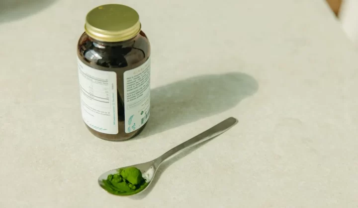 罐子和勺子装满绿色粉末特写,健康保健主题