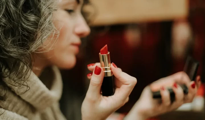 woman in gray sweater holding lipstick