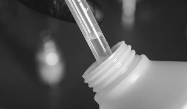 a person is holding a plastic bottle with a straw in it