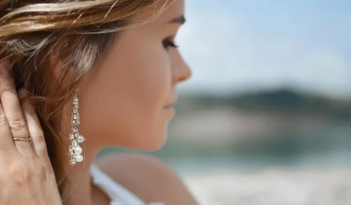 shallow focus photography of woman wearing dangling earrings holding her hair near mountain