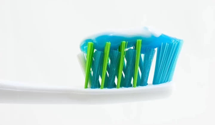 white, blue, and green toothbrush with blue toothpaste