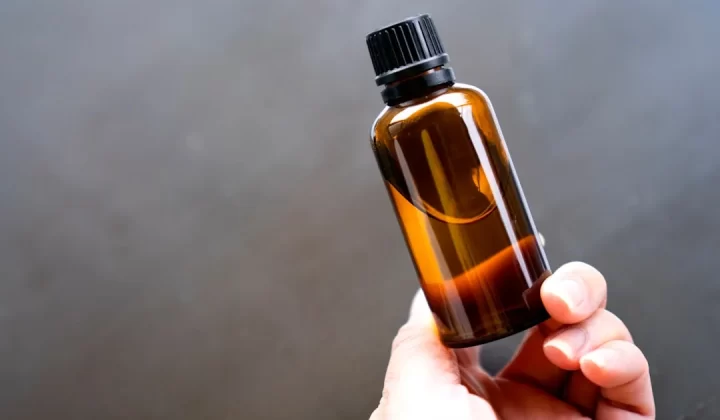 a person holding a bottle of essential oils