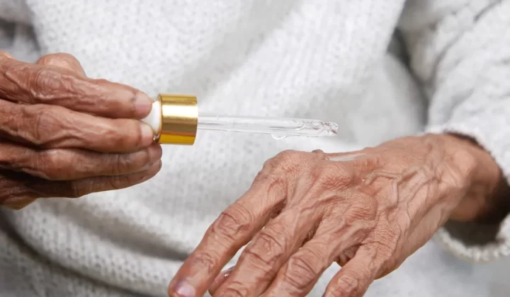 an older woman holding a small tube of liquid